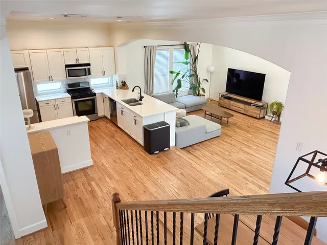 a living room with stainless steel appliances furniture a flat screen tv and a refrigerator