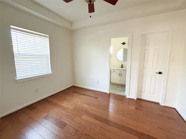 an empty room with wooden floor cabinet and windows
