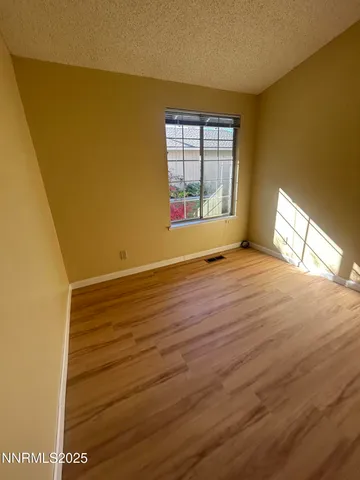a view of an empty room with a window and wooden floor