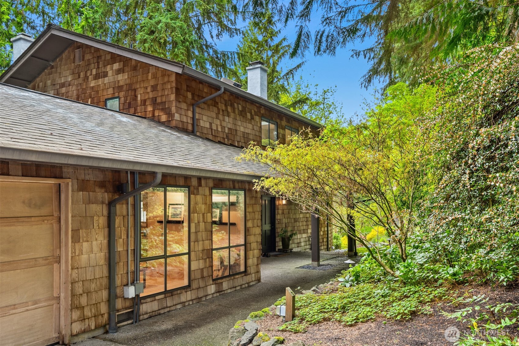 8151 Northeast Hidden Cove Road Bainbridge Island, WA 98110 - Photo 3 of 40 a backyard of a house with large trees and plants