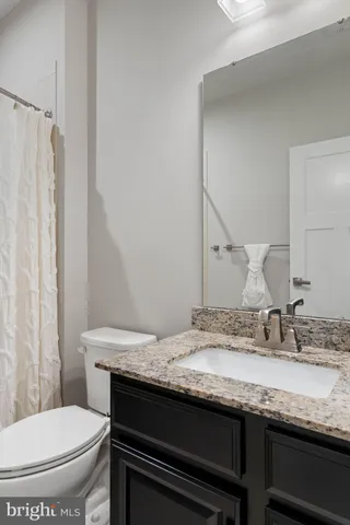 a bathroom with a granite countertop toilet sink and mirror