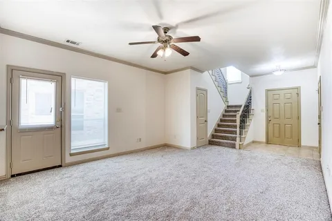an empty room with ceiling fan and windows