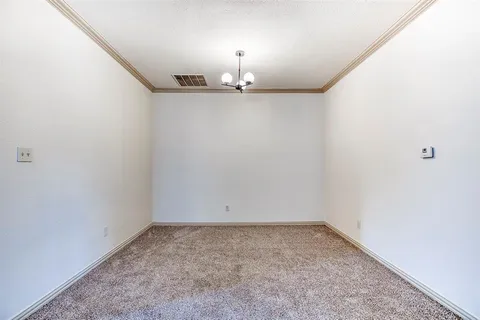 an empty room with chandelier fan and wooden floor