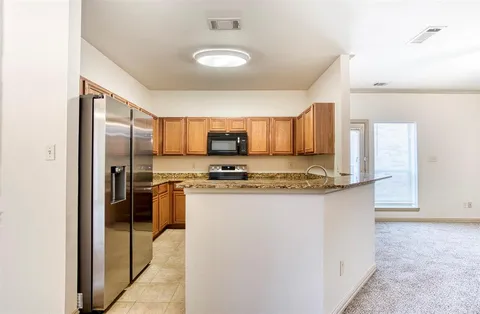 a kitchen with stainless steel appliances granite countertop a refrigerator a stove and a sink