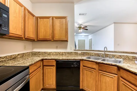 a kitchen with granite countertop stainless steel appliances white cabinets sink and a dishwasher