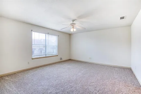 an empty room with windows and fan