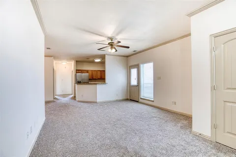 an empty room with a kitchen and a ceiling fan
