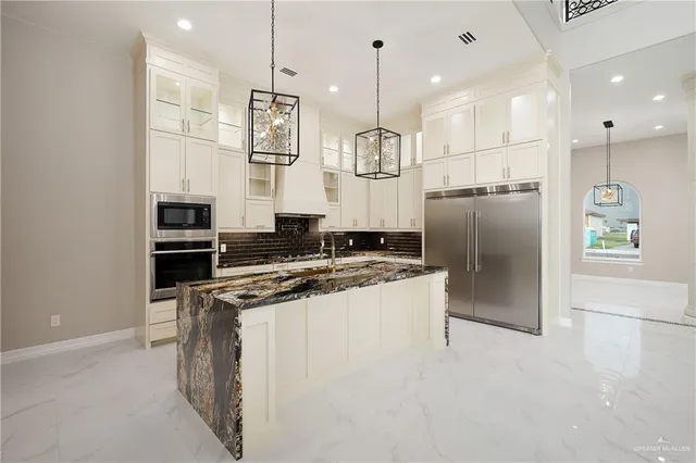 a kitchen with stainless steel appliances granite countertop a refrigerator a stove and a sink