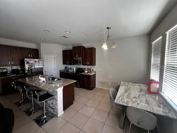 a kitchen with a dining table chairs and a refrigerator