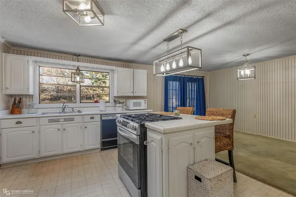 a kitchen with a stove a sink a window and dining table