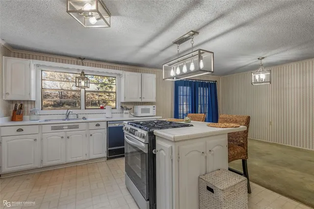 a kitchen with a stove a sink a window and dining table