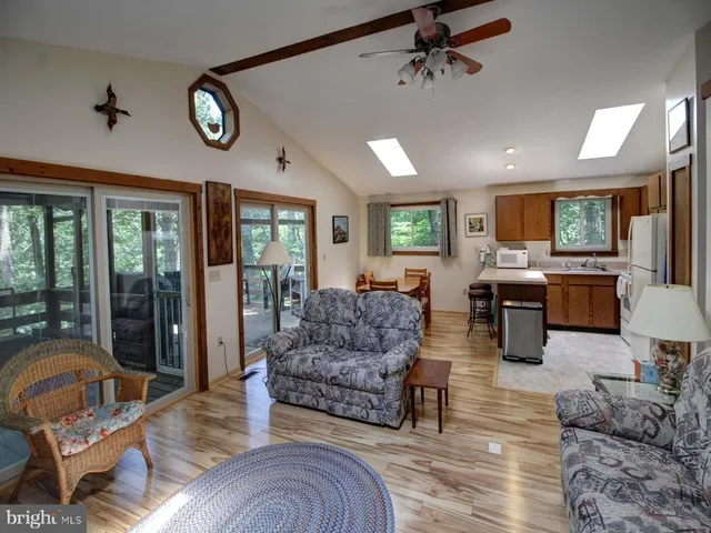a living room with furniture kitchen view and a large window