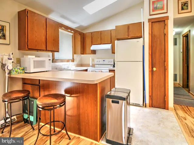 a kitchen with stainless steel appliances granite countertop a refrigerator a sink a stove and white cabinets with wooden floor