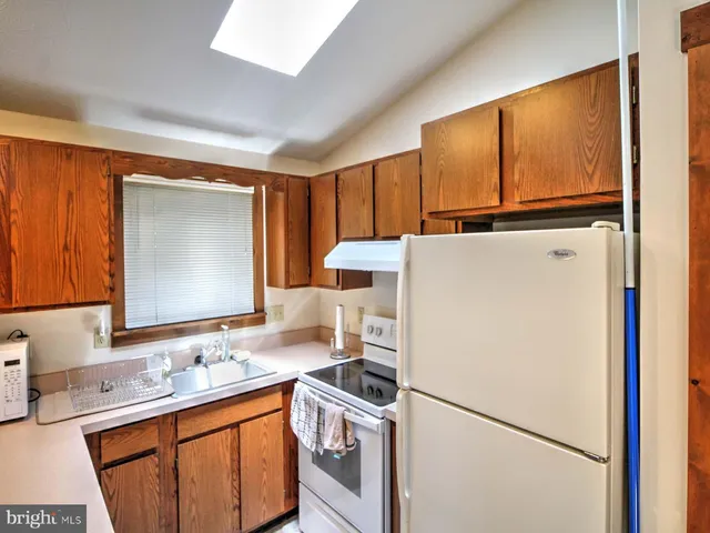 a kitchen with stainless steel appliances granite countertop a refrigerator a sink and a stove with white countertops