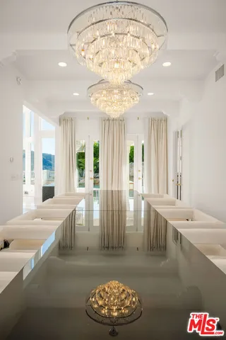 a view of a dining room with furniture a chandelier and kitchen view