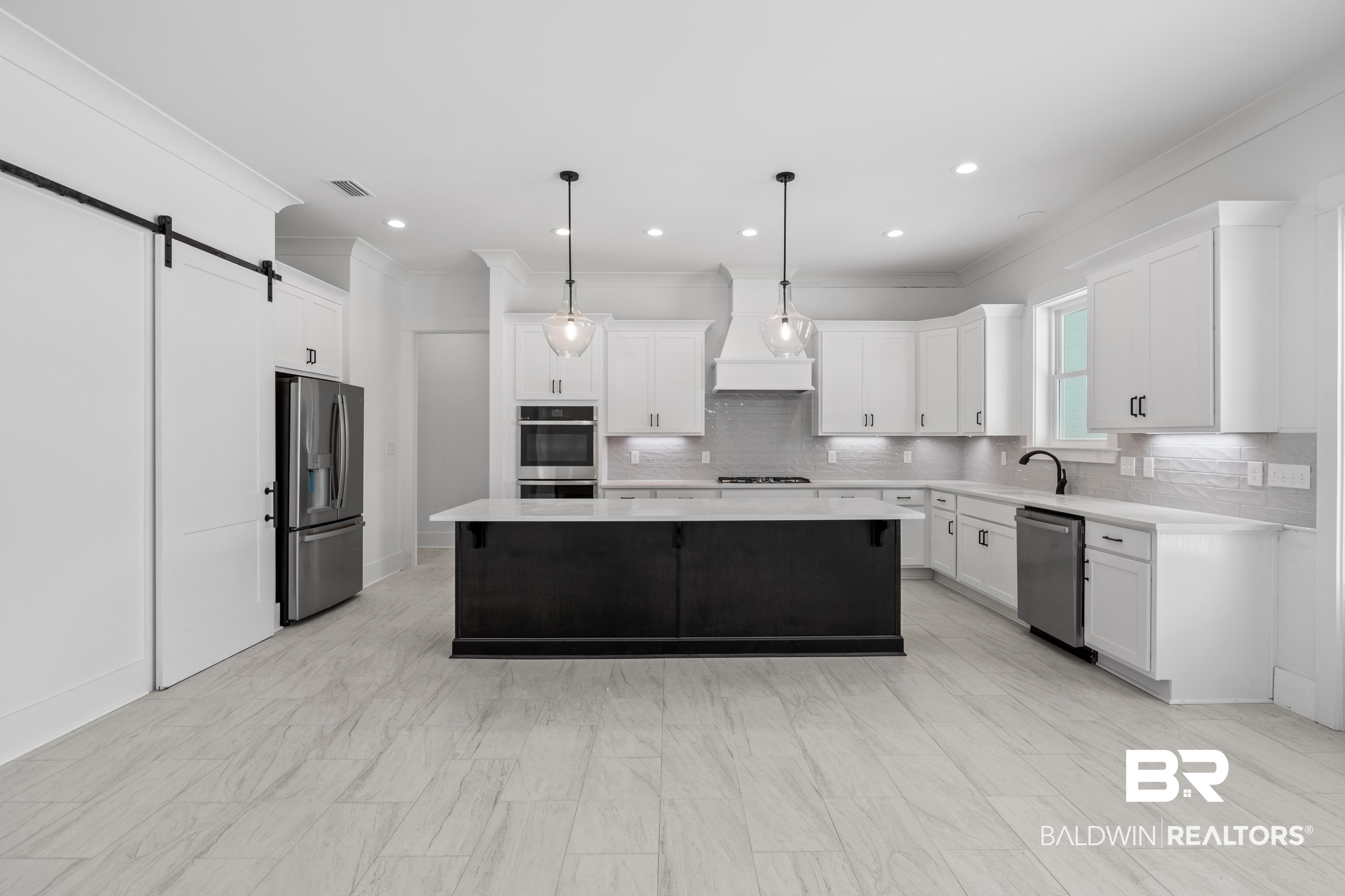 30650 Ono N Loop West Orange Beach, AL 36561 - Photo 13 of 38 Kitchen featuring appliances with stainless steel finishes, a barn door, light countertops, a center island, and crown molding