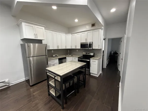 a kitchen with a refrigerator a microwave oven on a table and chairs