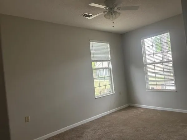 an empty room with a window and a fan