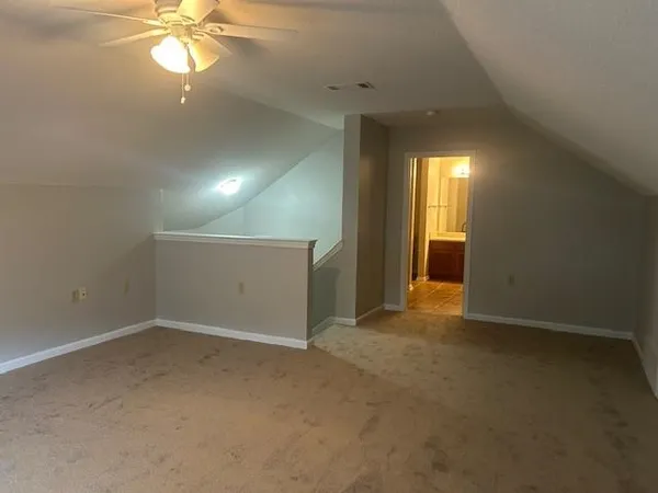 an empty room with a chandelier fan and closet area