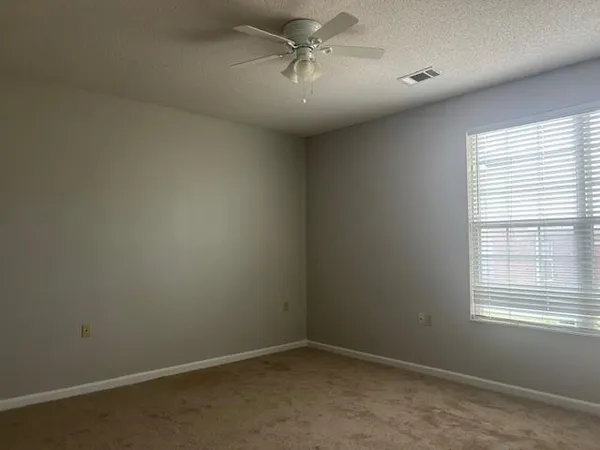 an empty room with windows and fan