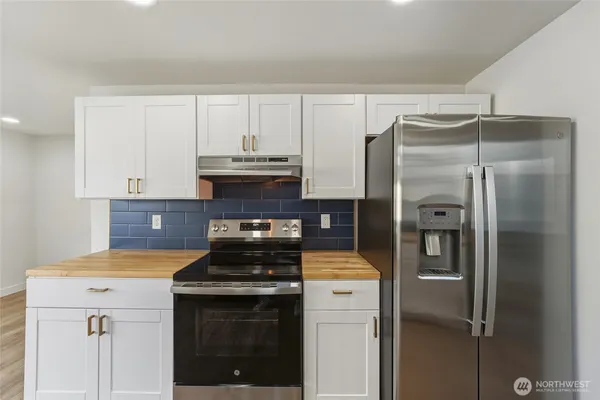 a kitchen with white cabinets and wooden floor