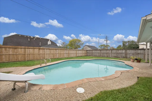 a view of a backyard with swimming pool and seating space