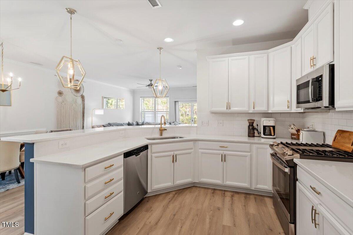 225 Mayfield Drive Apex, NC 27539 - Photo 11 of 41 a kitchen with stainless steel appliances granite countertop a sink stove and white cabinets with wooden floor
