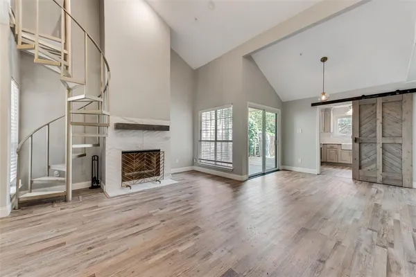an empty room with wooden floor fireplace and windows