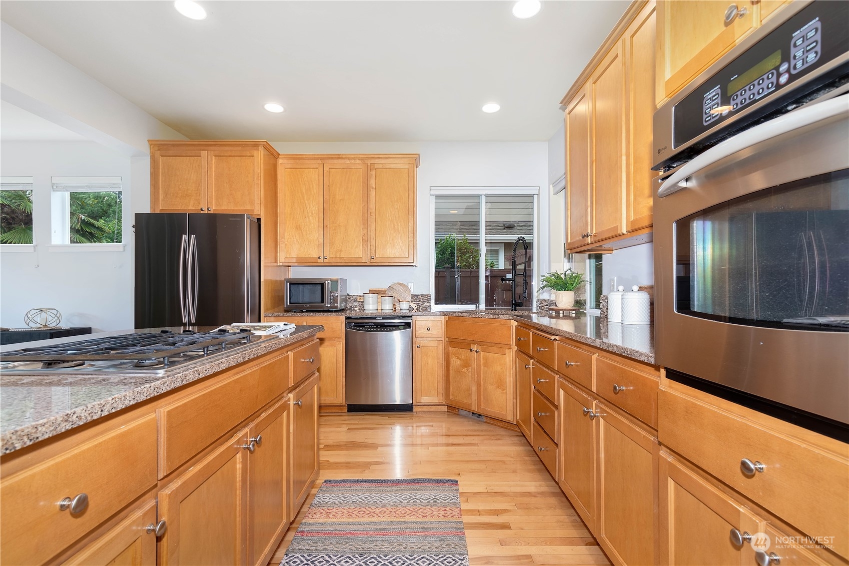 16722 166th Place Southeast Renton, WA 98058 - Photo 10 of 35 a large kitchen with stainless steel appliances granite countertop a refrigerator a oven a sink with wooden cabinets and glass windows