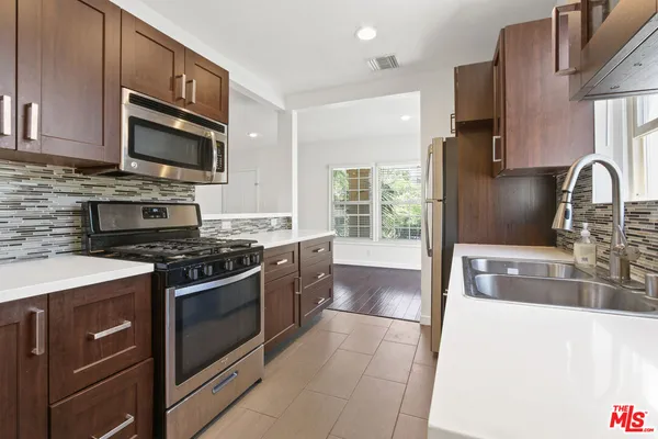 a kitchen with stainless steel appliances granite countertop a stove a sink and a microwave