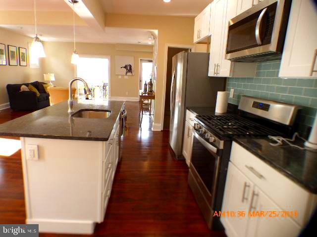 3102 Cedarhurst Road Baltimore, MD 21214 - Photo 11 of 42 a kitchen with stainless steel appliances granite countertop a refrigerator a stove and a sink with wooden floor
