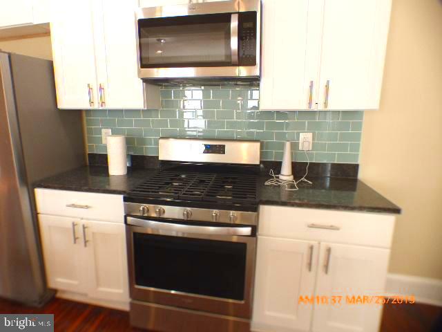 3102 Cedarhurst Road Baltimore, MD 21214 - Photo 13 of 42 a kitchen with granite countertop a stove and a white cabinet
