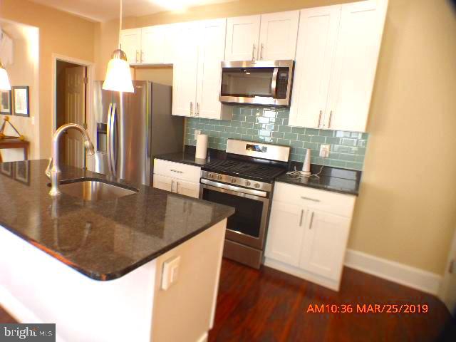 3102 Cedarhurst Road Baltimore, MD 21214 - Photo 10 of 42 a kitchen with stainless steel appliances a stove a sink a microwave and wooden cabinets