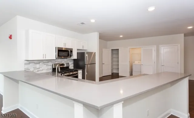 a kitchen with stainless steel appliances a sink a microwave a refrigerator and cabinets