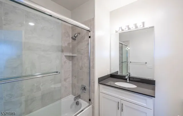 a bathroom with a granite countertop sink a mirror and a bathtub