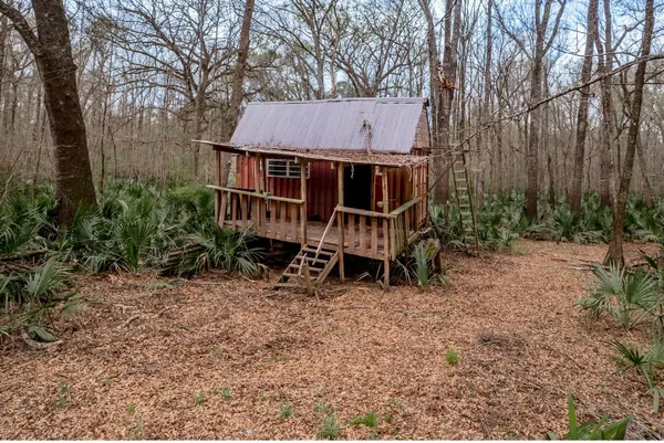 a view of a wooden house with a yard and sitting area
