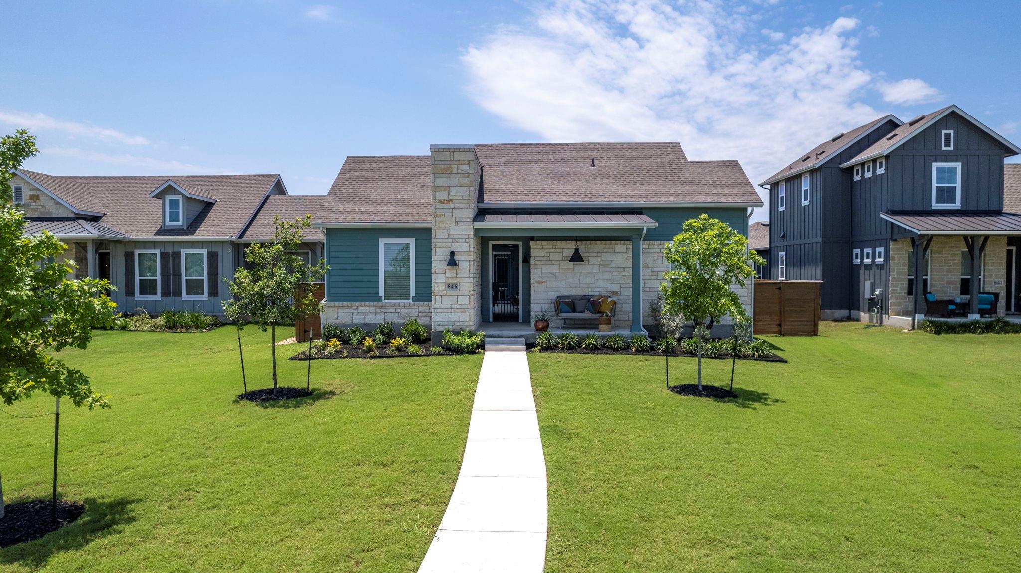 a front view of a house with garden and trees