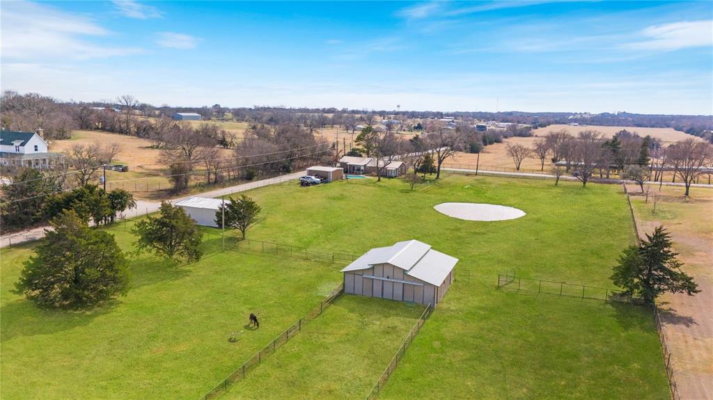 9213 Wilson Road Pilot Point, TX 76258 - Photo 3 of 36 Expansive green property featuring a large barn structure, secure fencing, and mature trees