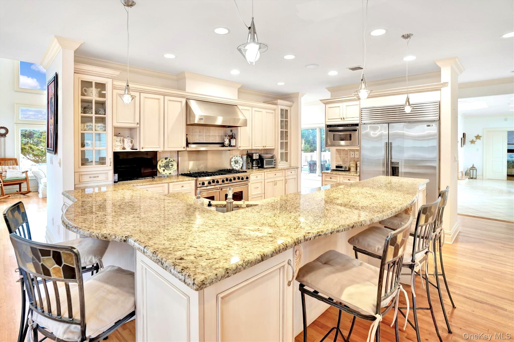 605 Dune Road Westhampton, NY 11978 - Photo 12 of 44 Kitchen with glass insert cabinets, cream cabinets, a kitchen bar, recessed lighting, and crown molding