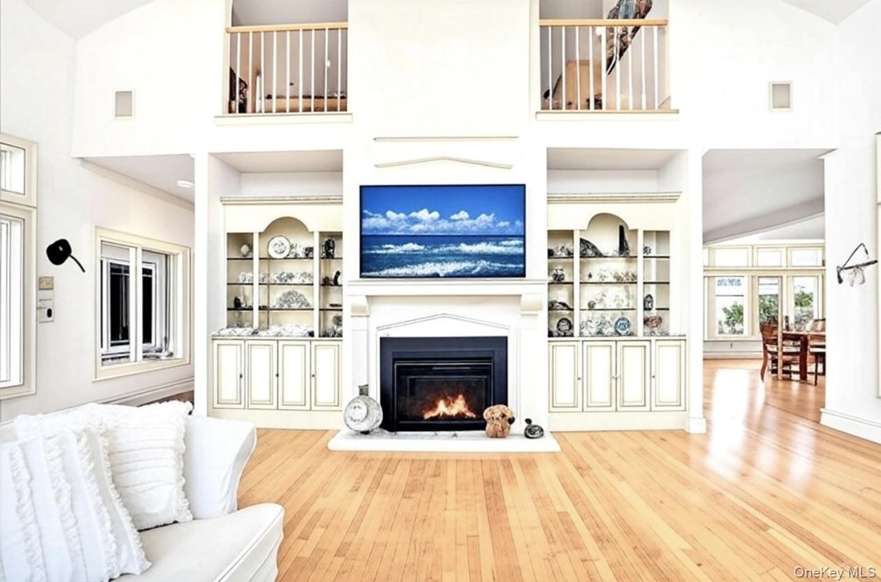 605 Dune Road Westhampton, NY 11978 - Photo 16 of 44 Living area featuring hardwood / wood-style flooring, a glass covered fireplace, high vaulted ceiling, and built in shelves