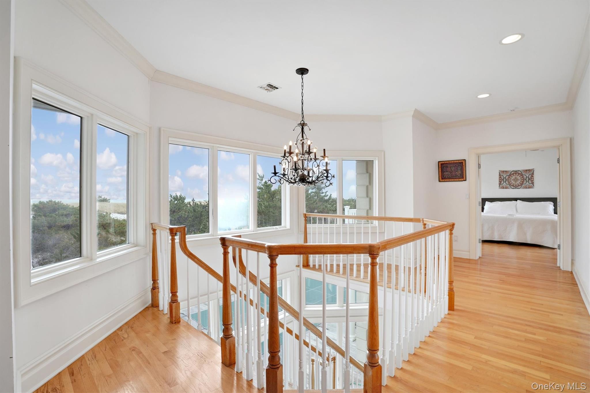 605 Dune Road Westhampton, NY 11978 - Photo 22 of 44 Corridor featuring an upstairs landing, Ocea. views, crown molding, light wood-style flooring, a chandelier, and recessed lighting