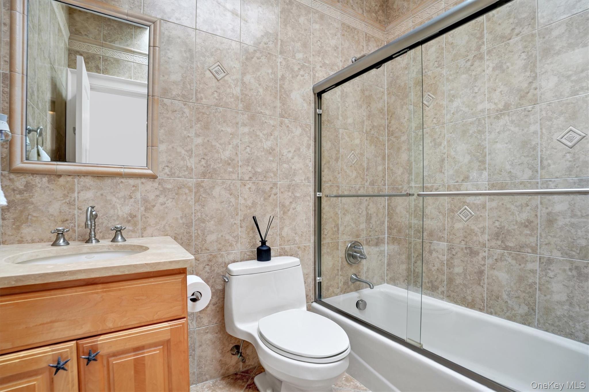 605 Dune Road Westhampton, NY 11978 - Photo 38 of 44 5th Bedroom en-suite Full bath featuring tile walls, vanity, bath / shower combo with glass door, and decorative backsplash