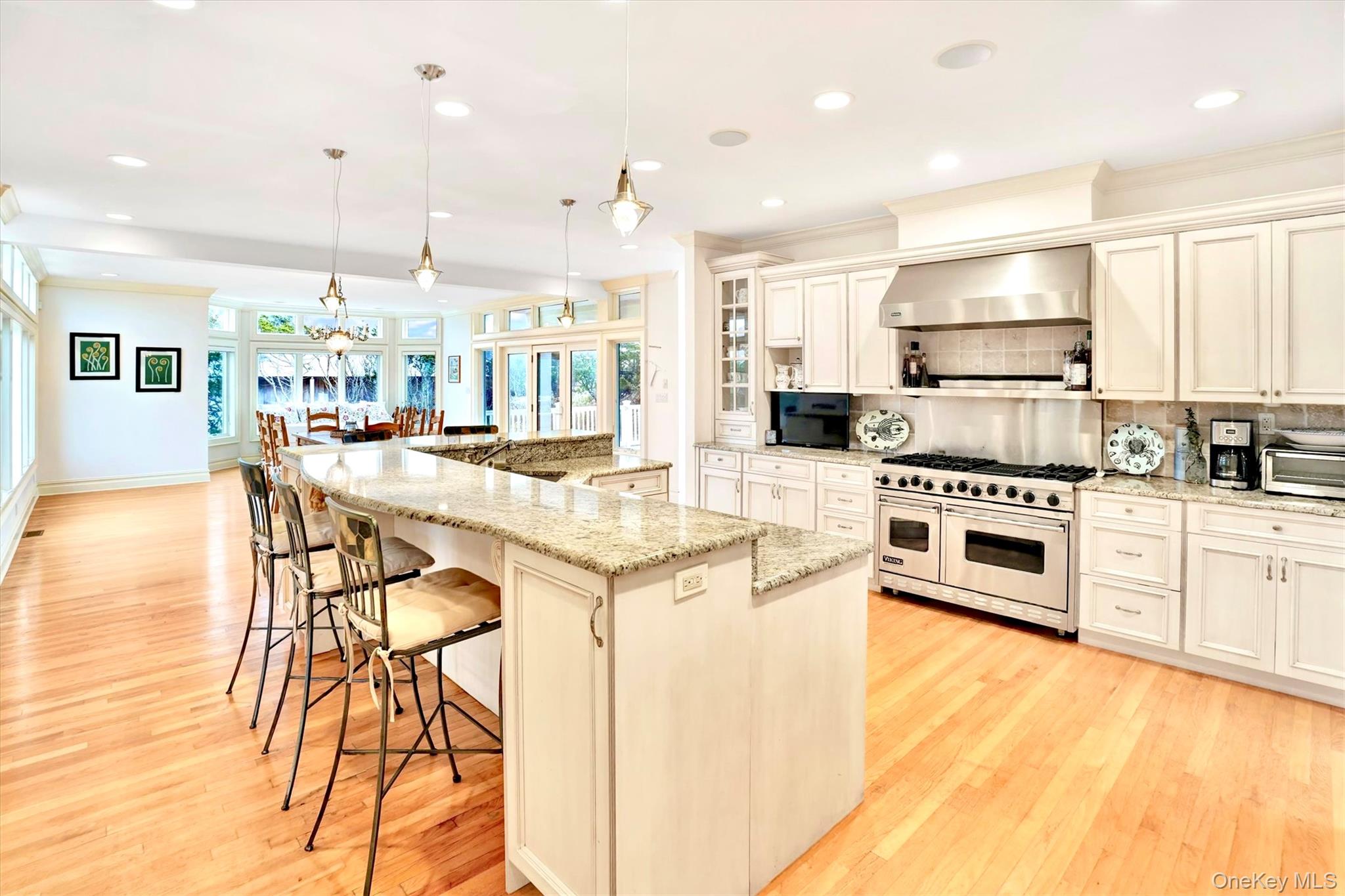 605 Dune Road Westhampton, NY 11978 - Photo 9 of 44 Chefs Kitchen featuring backsplash, Viking range with two ovens, a spacious island, light stone counters, and wall chimney exhaust hood.