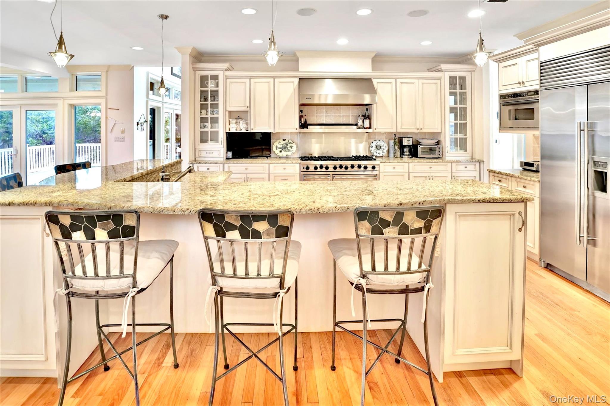 605 Dune Road Westhampton, NY 11978 - Photo 10 of 44 Kitchen featuring decorative light fixtures, cream cabinetry, premium appliances, recessed lighting, and light stone countertops. Subzero refrigerator and freezer.