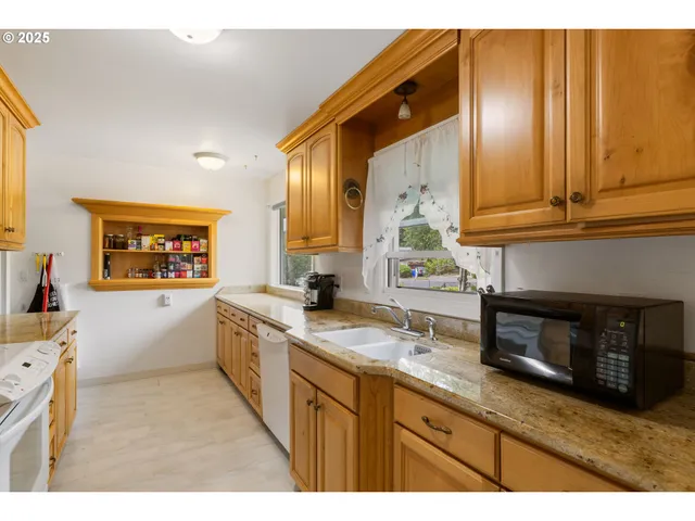 a kitchen with granite countertop a sink stainless steel appliances wooden floor and cabinets
