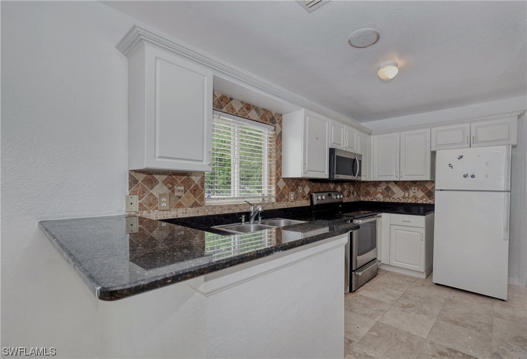 a kitchen with granite countertop a sink and white cabinets