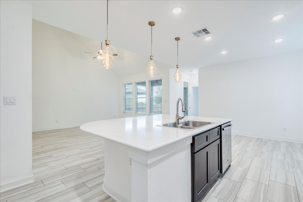 8008 Prairie Rye Drive Lago Vista, TX 78645 - Photo 23 of 40 Kitchen island with a white countertop and dark cabinetry, featuring an undermount stainless steel sink with a gooseneck faucet