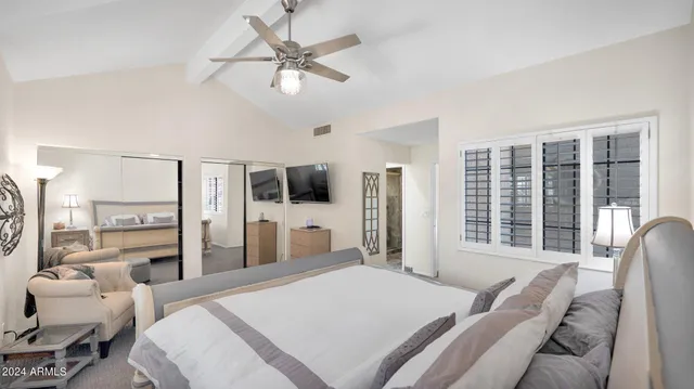 a bedroom with a bed a flat screen tv and a large window