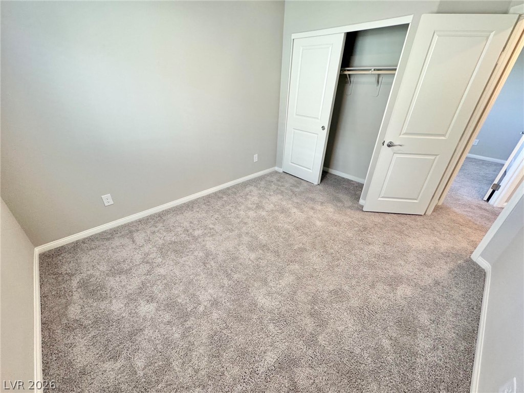 7020 Colonial Ranch Street Las Vegas, NV 89166 - Photo 23 of 37 Plush carpeting underfoot complements neutral walls in a quiet secondary bedroom featuring closet storage.