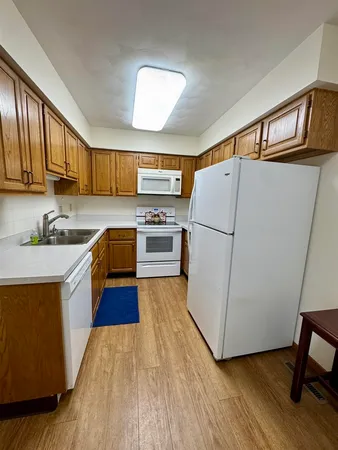 a kitchen with wooden floors and white stainless steel appliances